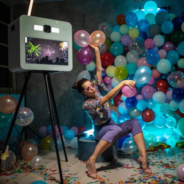 person taking a photo with a fancy photo booth camera with balloons in the back ground